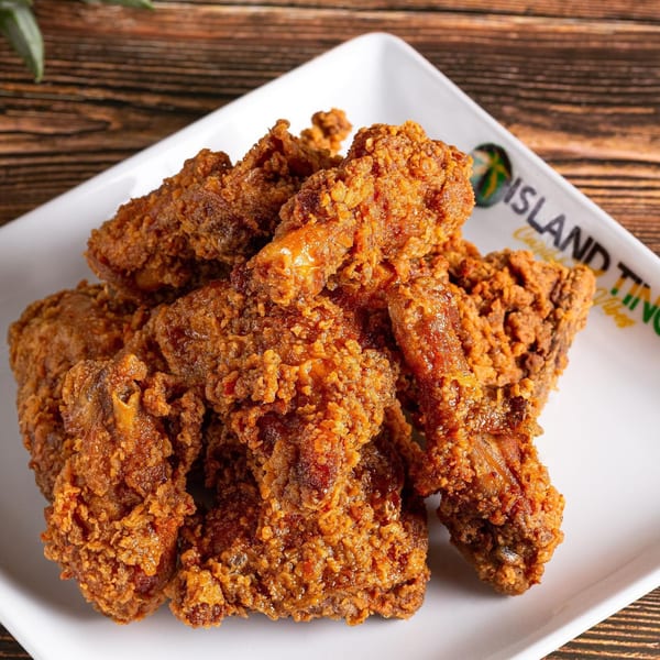 Crispy, golden-brown fried chicken pieces piled on a white rectangular plate with the Island Tings logo.
